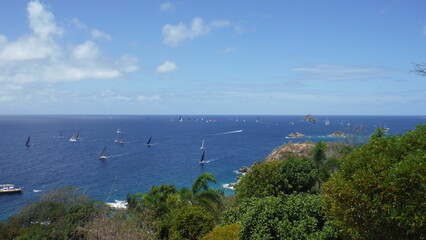 Sailboats sailing away on the Caribbean sea during a race or an event located in Saint-Barthélémy, French West Indies.