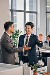 two men in suits are standing in an office with a laptop