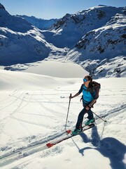 Panorama view in the Alps. Young woman on a ski tour on the ascent to the Etscherzapfenn in the background Lake Murgsee in the Glarus region. Ski mountaineering in the beautiful Swiss mountains
