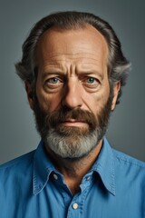 arafed man with a beard and a blue shirt looking at the camera