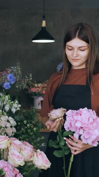Young beautiful woman designer of floral arrangements chooses flowers for a bouquet in a flower shop. Retail sale of flowers, small business. Making a bouquet in a flower shop, a young woman desinger
