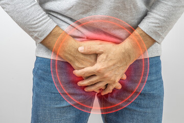 Men's health concept. Man holding his lower abdomen, suffering from pain or cramping.