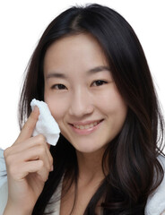 A woman with light skin and dark hair applies a white powder puffs to her cheek. The background is plain white.