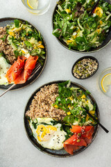 Delicious healthy breakfasts, green buckwheat with fried egg and spinach and red salmon fish, mix salad with fresh herbs and peppers and seeds, healthy balanced breakfast with fats, fiber and protein