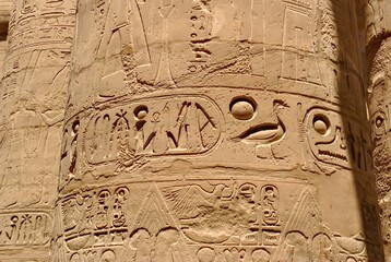 Close-up view of intricate hieroglyphic carvings on a sandstone column at Karnak Temple, highlighting ancient Egyptian symbols and artistic details under sunlight.