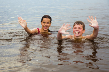 A girl and a boy swim in a fresh lake. © Sergei