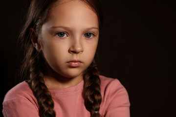 Orphanage concept. Sad girl on black background