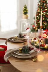 Christmas celebration. Festive table setting with dishware, glasses and decor in room