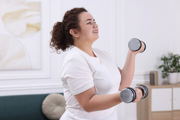 Plus size woman with dumbbells training at home