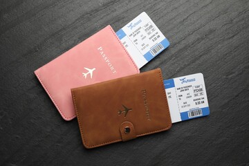 Travel agency. Flight tickets and passports on dark textured table, flat lay