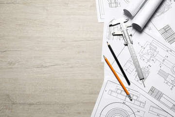 Different engineering drawings, vernier caliper and pencils on wooden table, top view. Space for...
