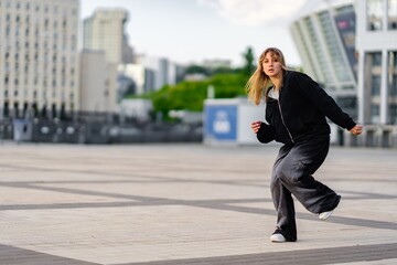 Fototapeta premium A young woman wears oversized clothes and dances hip-hop.