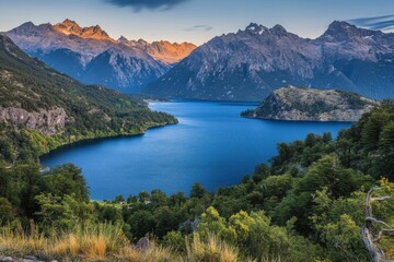 Fototapeta premium Stunning view of a serene lake surrounded by towering mountains during sunset. The warm light casts a golden glow on the peaks, reflecting a beautiful landscape