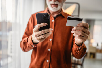 close up of senior man hands hold credit card and mobile phone