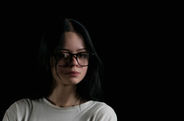 Portrait image of a young girl with glasses in the dark