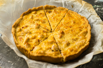 Delicious French quiche pie with chicken and cheese. Baking process, pie cooling on baking parchment