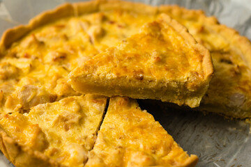 Delicious French quiche pie with chicken and cheese cut into pieces, on a dark background with place for text, copy space. Food blog concept, writing recipes