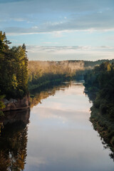 scenic view of the river where the background is forests over forests fog and the evening sun shines