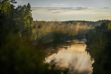 scenic view of the river where the background is forests over forests fog and the evening sun shines