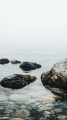 Tranquil Seascape with Rocks and Calm Water Under Foggy Sky