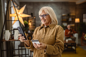 Fototapeta premium senior mature woman buy online on cellphone with credit card