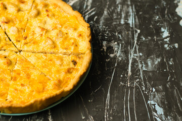 Delicious French quiche pie with chicken and cheese cut into pieces, on a dark background with place for text, copy space. Food blog concept, writing recipes