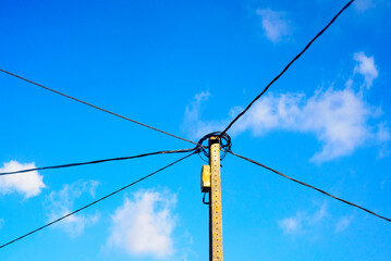 Cables en poste de hormig&oacute;n sobre cielo azul