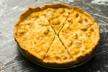 Delicious French quiche pie with chicken and cheese cut into pieces, on a dark background with place for text, copy space. Food blog concept, writing recipes