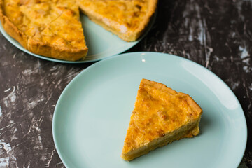 Flatlay, a piece of delicious open quiche pie with chicken, cheese and cream on a turquoise plate. Concept of food blog, writing recipes.