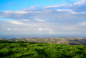 Pequeño arco iris en el horizonte marino desde monte