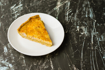 Flatlay, a piece of delicious open-faced quiche pie with chicken, cheese and cream on a white plate. Concept of food blog, writing recipes.