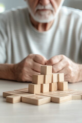 Senior man with cognitive disorder sitting at table in geriatric clinic playing wooden cubes board game. Cognitive disorder, brain exercises. Dementia, Alzheimers, care 