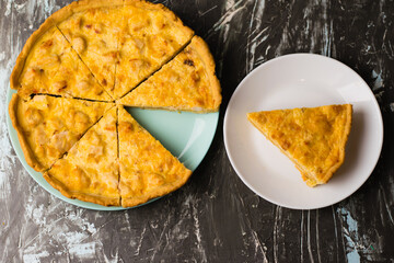 Flatlay, a piece of delicious open-faced quiche pie with chicken, cheese and cream on a white plate. Concept of food blog, writing recipes.