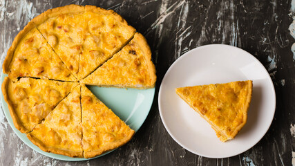 Flatlay, a piece of delicious open-faced quiche pie with chicken, cheese and cream on a white plate. Concept of food blog, writing recipes.