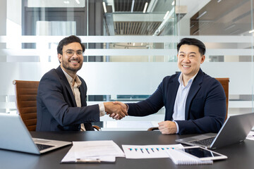 Handshake, two businessmen inside the office, business meeting agreeing on a contract, men smiling...