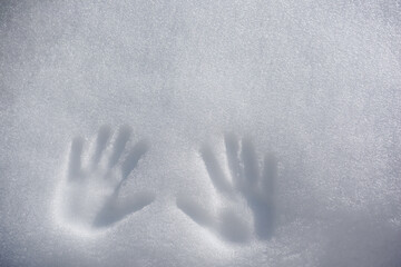 Visible handprints gently pressed into sparkling white snow. This winter moment reflects creativity and the beauty of fresh, untouched snow under a crisp.