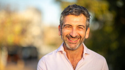 Smiling man outdoors in warm sunlight with blurred background