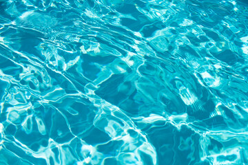 Water background. Blue water, ripples and highlights. Texture of water surface and tiled bottom.