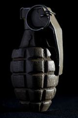 Close-up of an American World War Two "pineapple" hand grenade. The hand grenade is side-lit against a black studio background