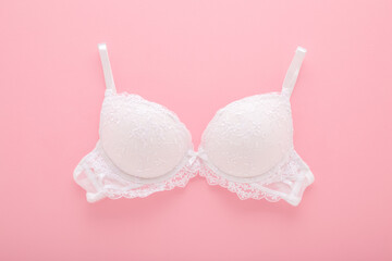 New white lace bra on light pink table background. Pastel color. Female casual underwear. Closeup....