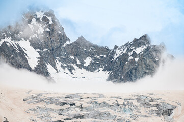 Obraz premium Silhouettes of mountain range with glacier during snowfall in the Alps. Mont Blanc massif. Weather. Climate change 