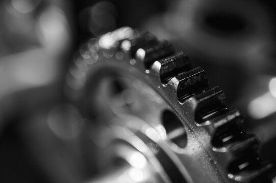 Black and white close-up of metal gears and mechanical parts symbolizing industrial equipment, precision engineering and mechanical processes, selective focus