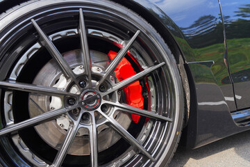 Alloy wheel with calipers and racing brakes of the sport car. Racing brake disc and low profile tyres. Race car test driving. Lower-profile tires of drag and drift cars. High-performance sports cars.