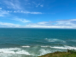 View of the rough ocean from the shore with coastal vegetation - Torres, Brasil