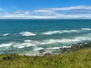 View of the rough ocean from the shore with coastal vegetation - Torres, Brasil