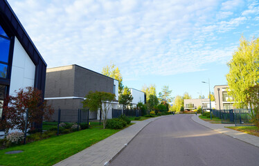 Obraz premium Modern luxury Villa. Street Road in Contemporary Residence. Modern Prefab house. Home with lawn, shrubs, green courtyard in sustainable enviroment. Family House in Gated Community. Landscaping at home