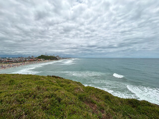 View of the rough ocean from the shore with coastal vegetation - Torres, Brasil