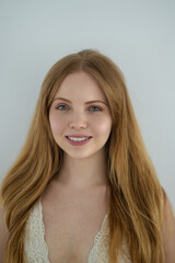 Happy girl. Close up face of young woman with beautiful smile isolated on grey wall with copy space. Cute girl. Woman looking at camera against gray wall with a whitening teeth smile.
