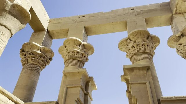 Contemplating the massive pillars of the Philae temple at the Majestic Shrine of Isis in Aswan. Testimony of the greatness of this ancient Egyptian temple in the middle of the Nile river in Egypt.