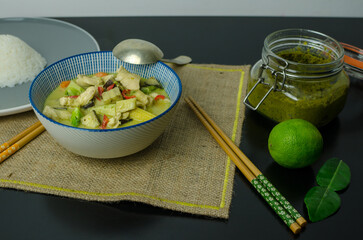 Thai Green Chicken Curry with rice in a bowl on a black table, top view